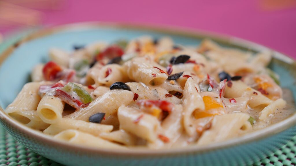 Delicious creamy Alfredo pasta with colorful vegetables served in a bowl, capturing a vibrant and appetizing look.